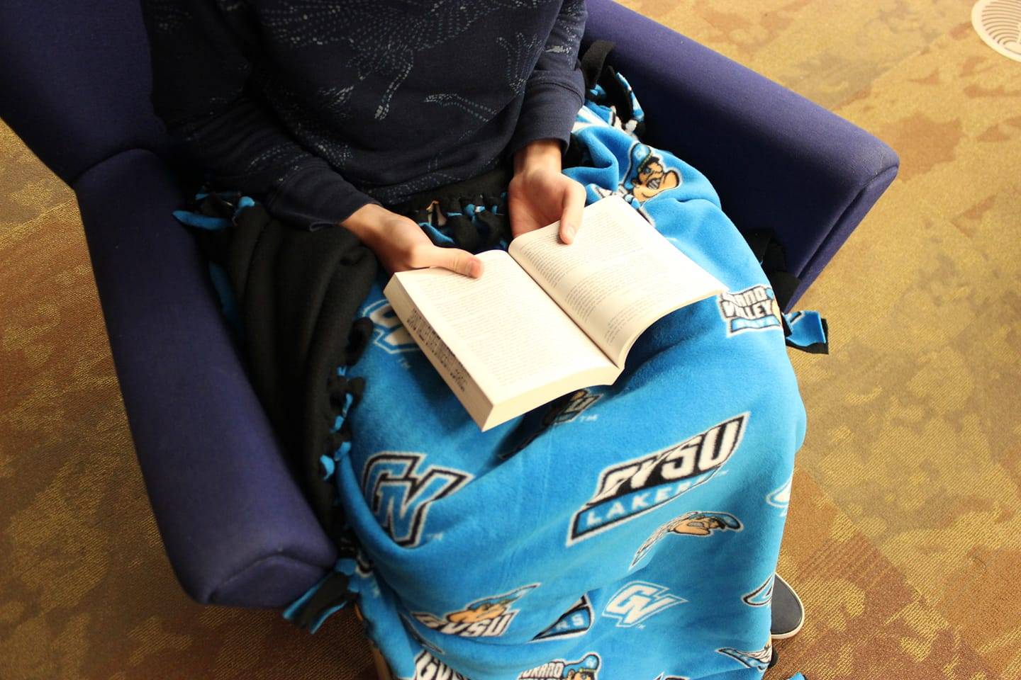Person reading and wearing gvsu DIY blanket